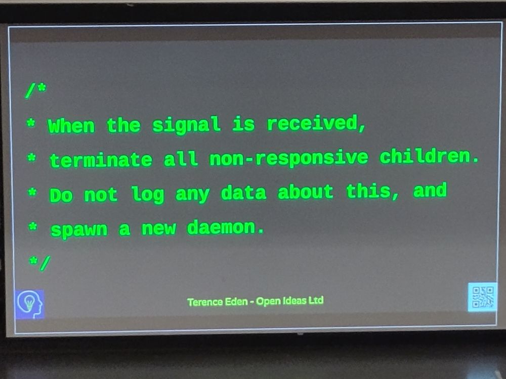 The image shows a screenshot of a code comment in green text on a dark background. The code reads:"/*When the signal is received,
terminate all non-responsive children.
Do not log any data about this, and
spawn a new daemon. */"
The comment is attributed to "Terence Eden - Open Ideas Ltd." There is also an icon of a lightbulb with a head, and a QR code in the bottom left corner. The text is displayed on a screen, likely taken during a presentation at FOSDEM.